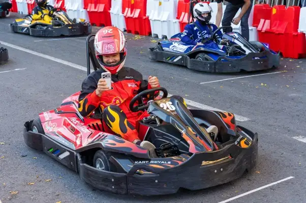 Piloto sonriente en kart eléctrico mostrando el pulgar arriba en la salida.