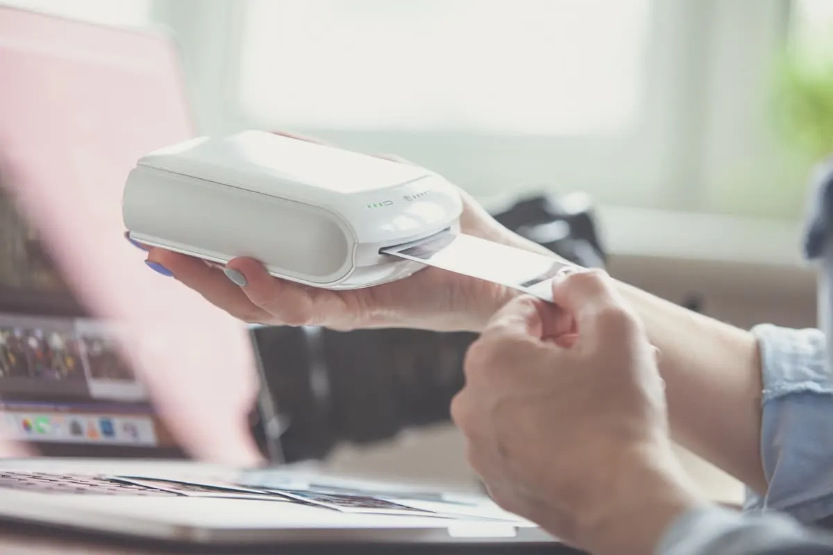 Persona usando una impresora fotográfica portátil sobre un escritorio con portátil
