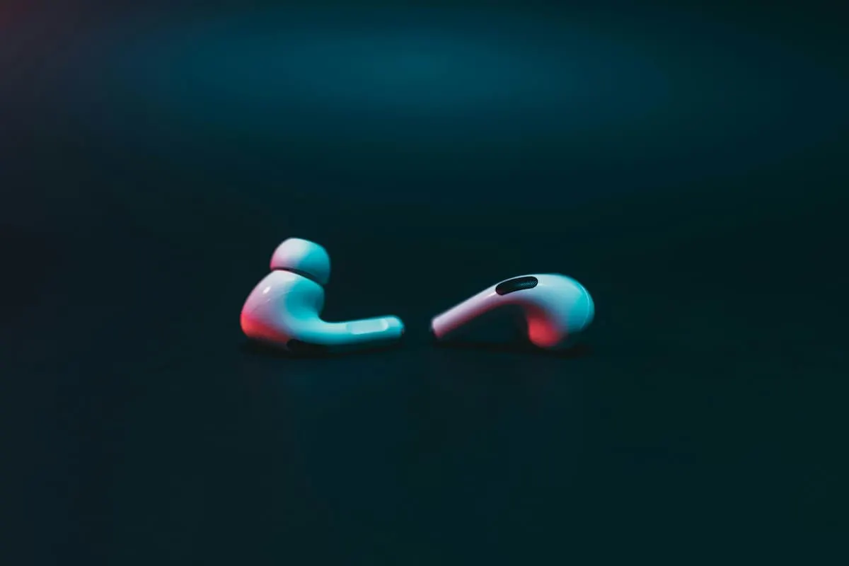 Auriculares inalámbricos blancos sobre fondo oscuro con luces de colores.
