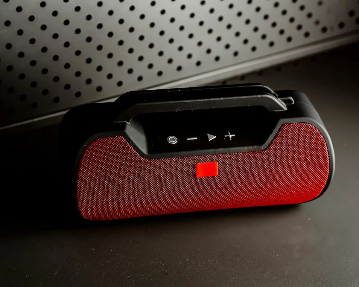 Altavoz Bluetooth portátil rojo y negro sobre una superficie.