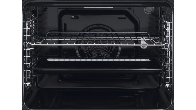 Interior de horno negro con rejillas metálicas y bandeja en la parte inferior. Un ventilador es visible en la parte posterior.