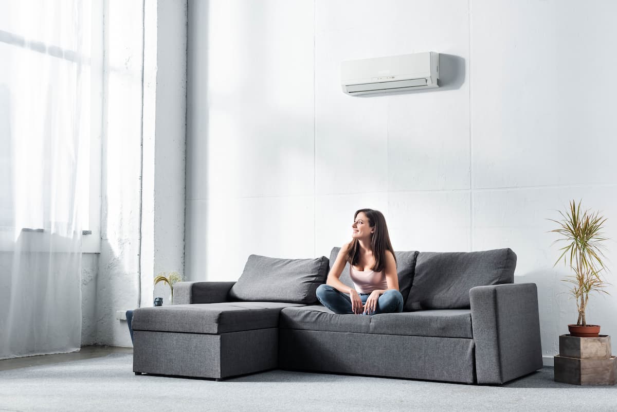 Mujer sentada en el sofá disfrutando del aire acondicionado split en el salón