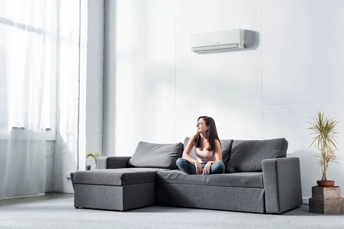 Mujer sentada en el sofá disfrutando del aire acondicionado split en el salón