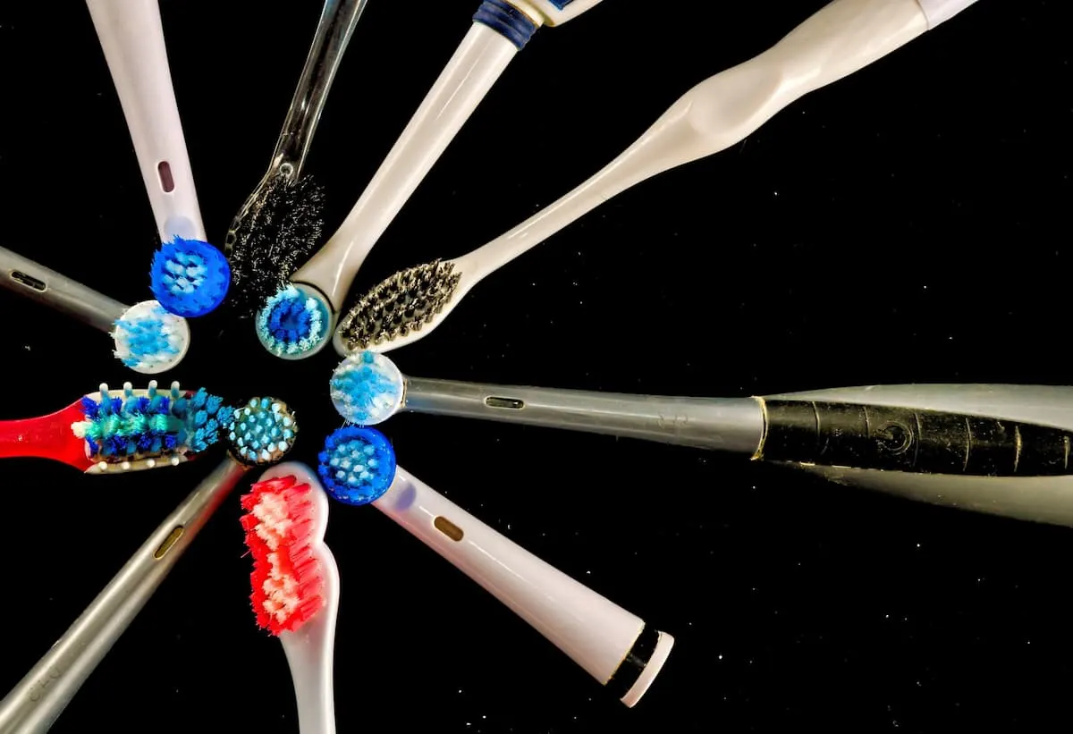 Varios cepillos de dientes eléctricos de distintos modelos y colores dispuestos en forma radial con los cabezales al centro, sobre fondo negro.