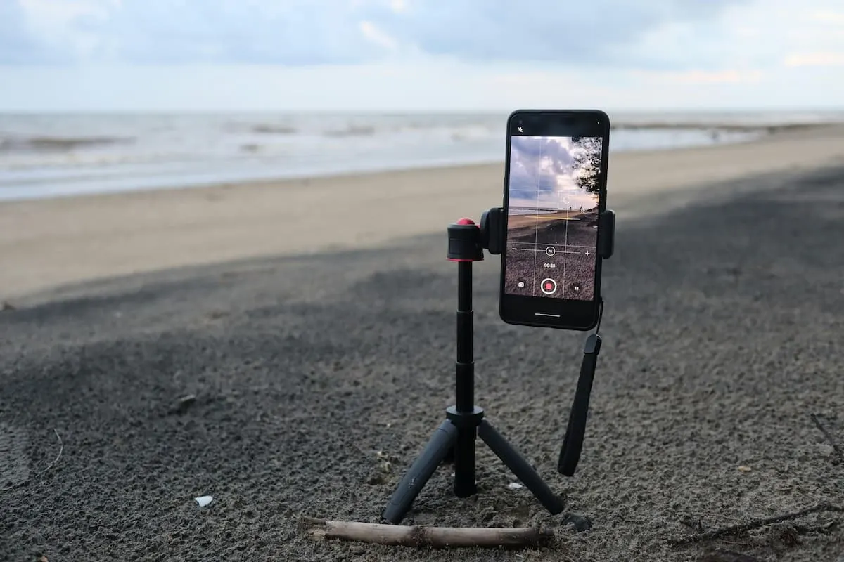 Smartphone en trípode grabando la playa.