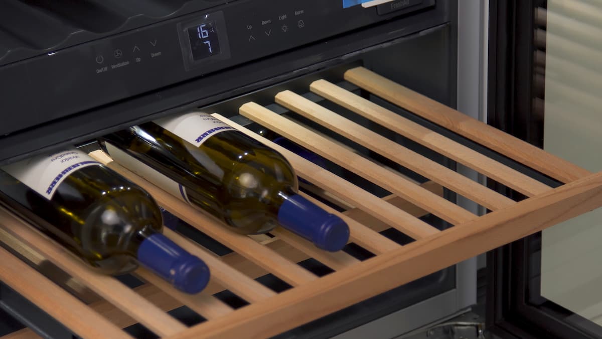 Cajón de madera de una vinoteca con dos botellas de vino, mostrando la temperatura en el panel digital.