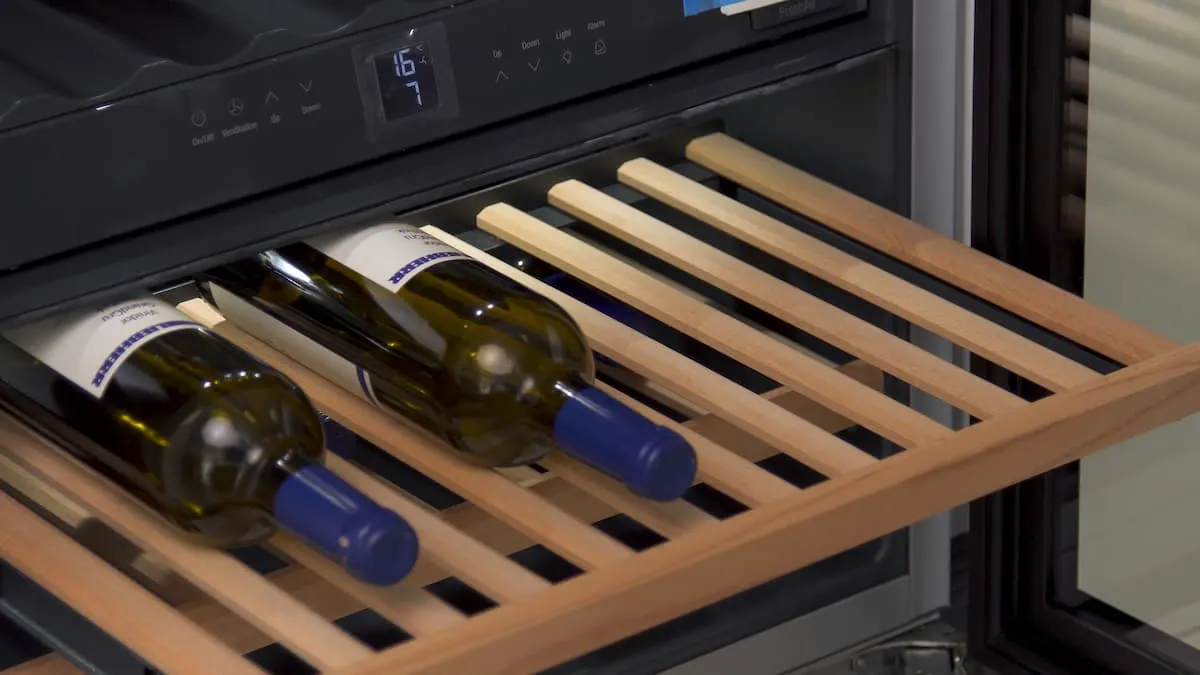 Cajón de madera de una vinoteca con dos botellas de vino, mostrando la temperatura en el panel digital.