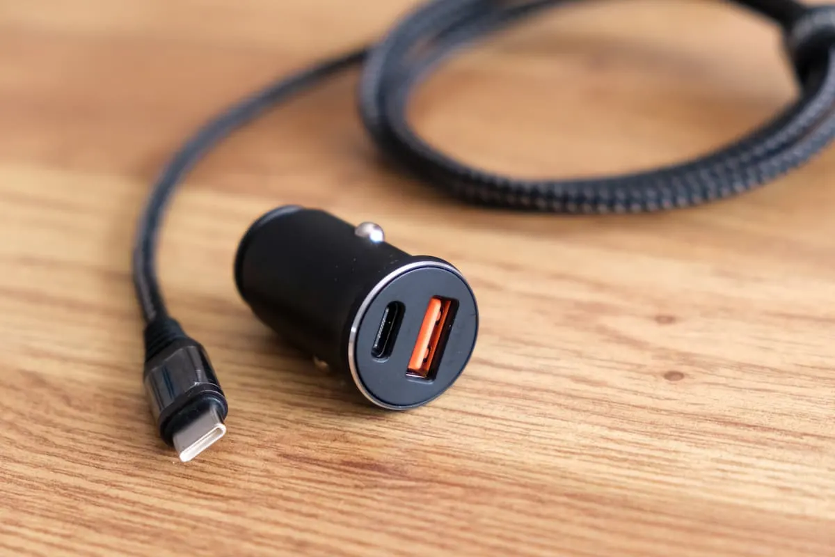 Cargador de coche con puerto USB-C y USB-A sobre superficie de madera