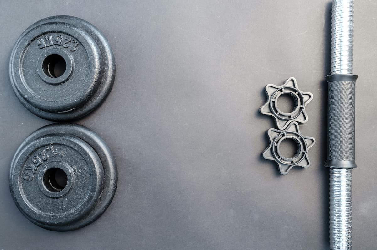 Componentes de mancuerna ajustable sobre fondo gris.