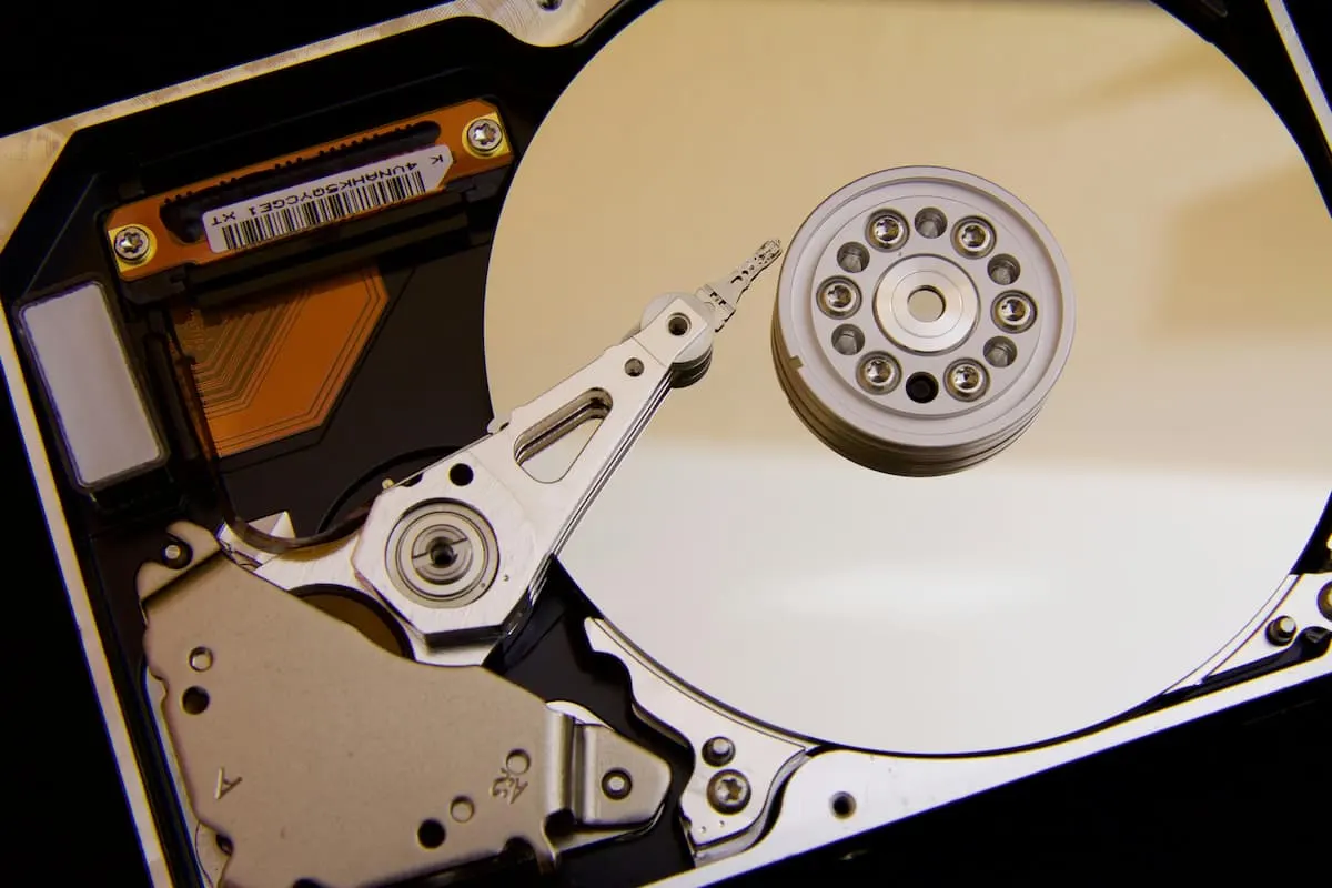 Interior de un disco duro HDD con el brazo lector sobre el plato metálico.
