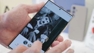 Una persona sostiene un teléfono móvil que muestra una foto en blanco y negro de una persona y un perro.