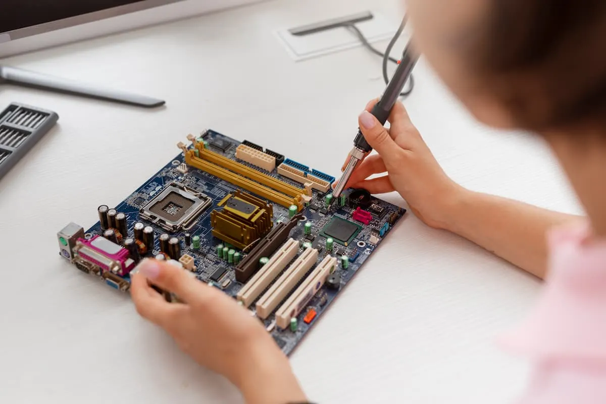 Persona reparando una placa base con un soldador.