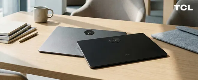 Dos tablets TCL sobre un escritorio de madera junto a una taza y cuadernos, en un entorno de trabajo luminoso.