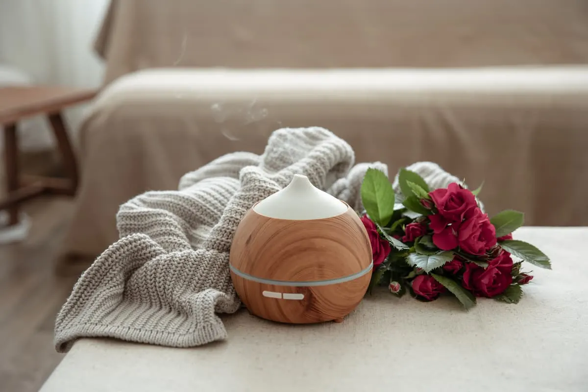 Humidificador de diseño madera junto a manta y rosas rojas.