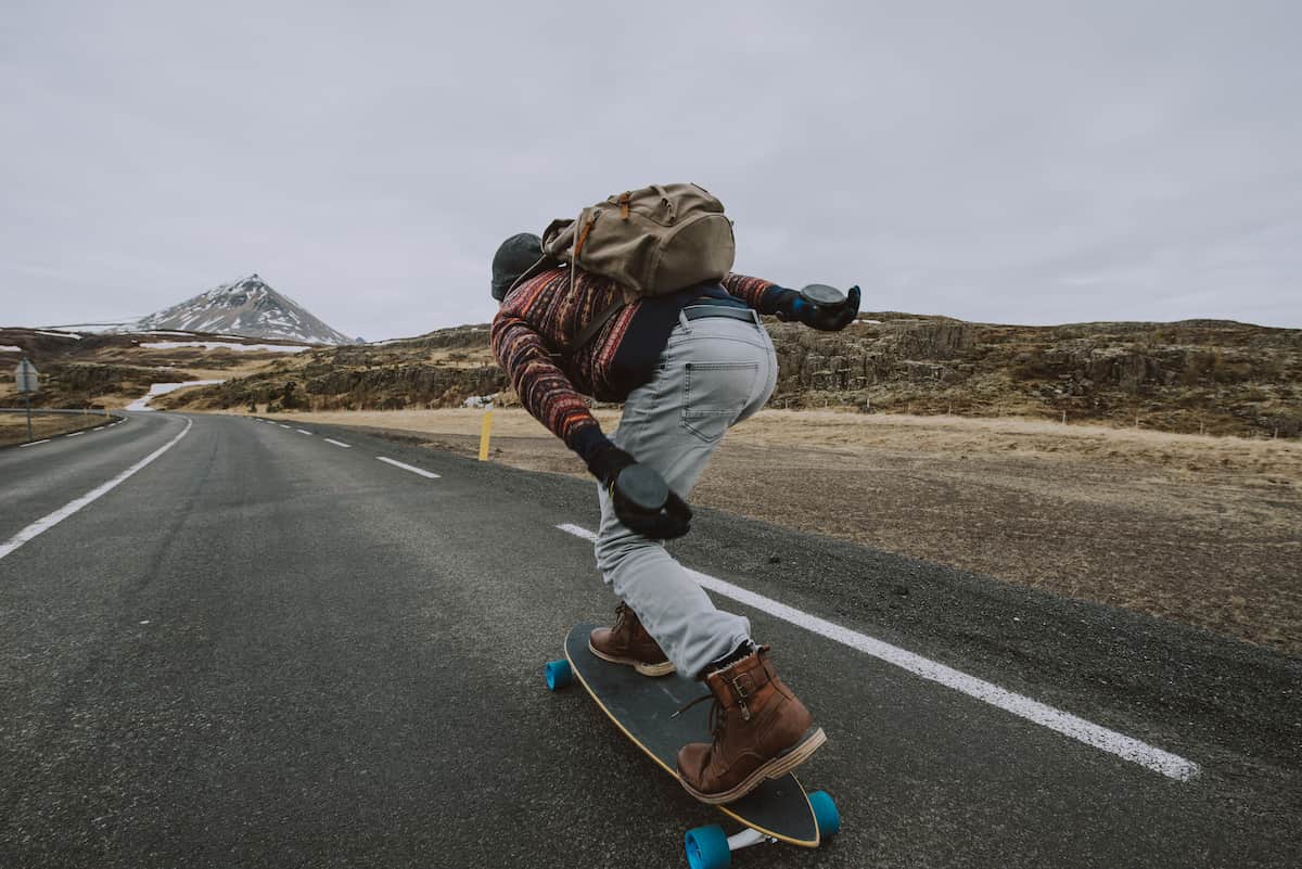 Persona haciendo longboard en una carretera abierta con montañas al fondo