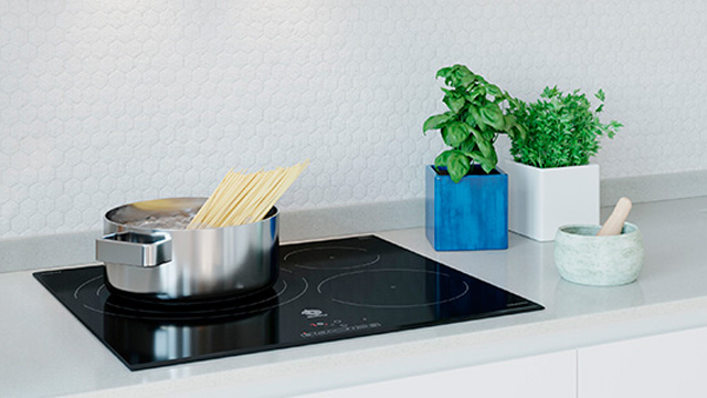 Detalle de una olla con agua hirviendo y espaguetti sobre una placa de inducción