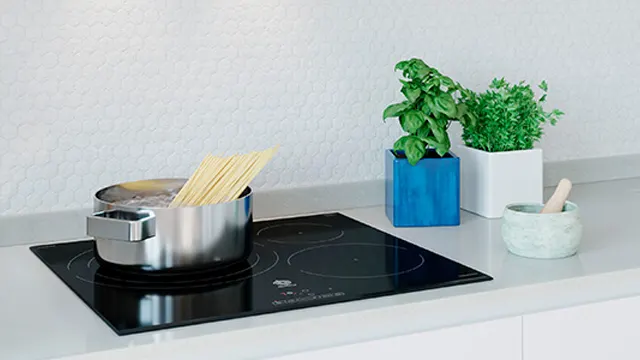 Detalle de una olla con agua hirviendo y espaguetti sobre una placa de inducción