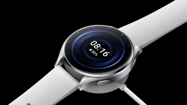 Reloj digital plateado con correa blanca, mostrando la hora 08:16 y un nivel de batería del 80%, conectado a un cargador.