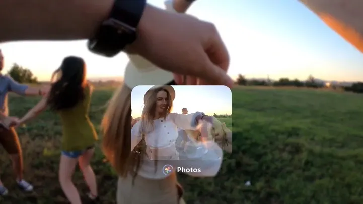 Un grupo de personas tomadas de las manos en un campo verde al atardecer, con un reloj en la muñeca en primer plano.