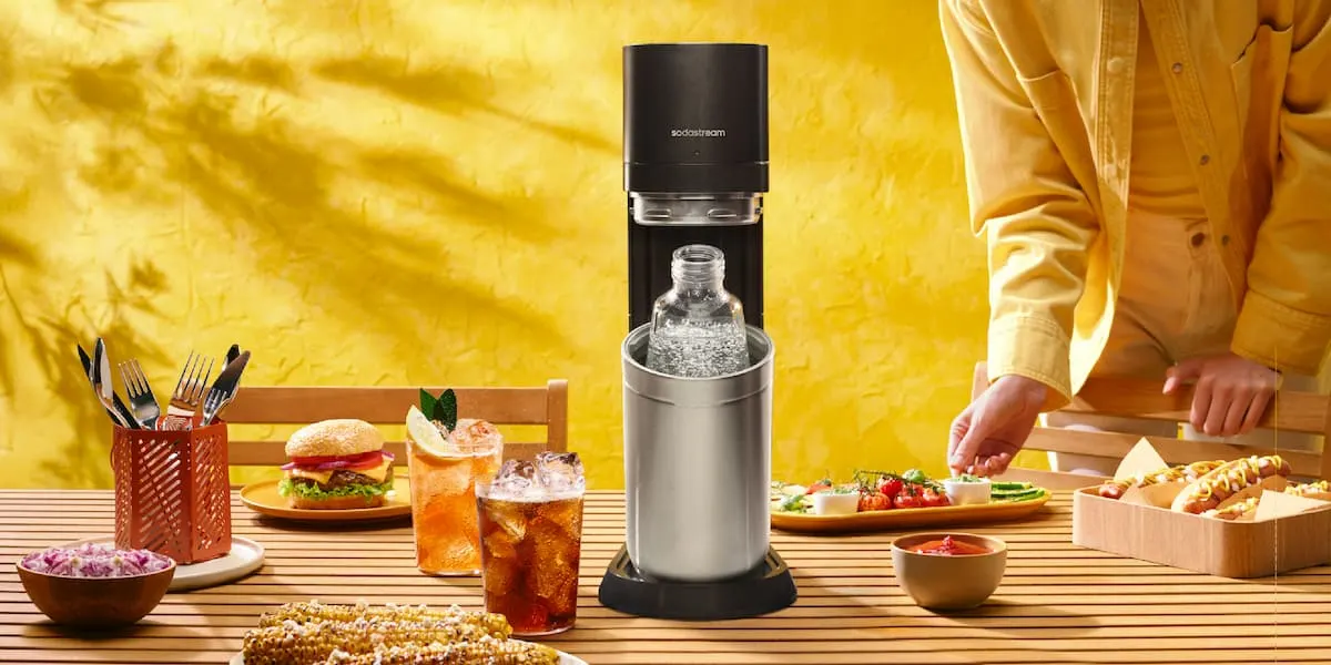 Gasificador SodaStream sobre mesa con comida y bebidas con gas