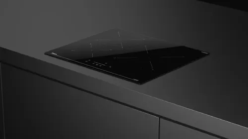 Placa de inducción negra de diseño minimalista, integrada en una encimera oscura.