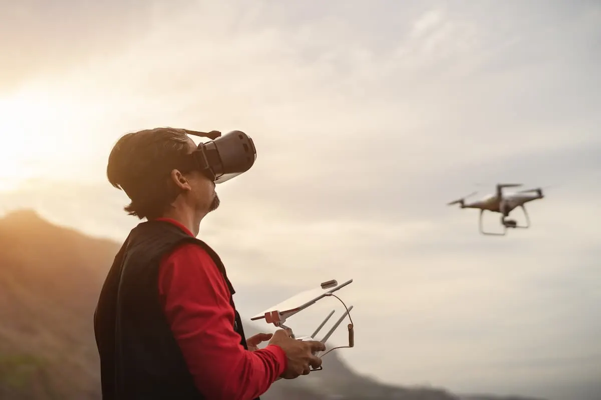 Persona con gafas de realidad virtual controlando un dron al atardecer.