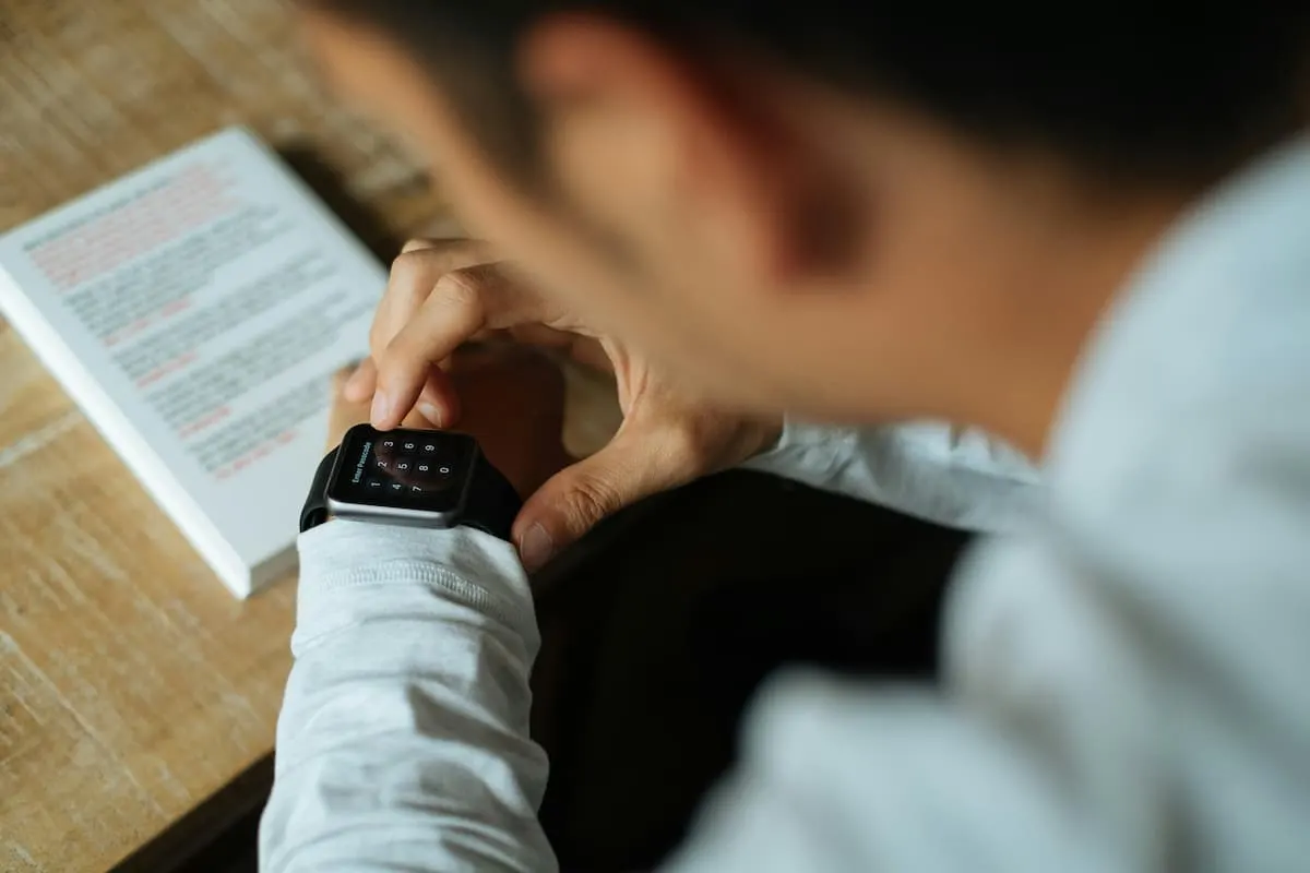 Persona usando un smartwatch mientras lee un libro.