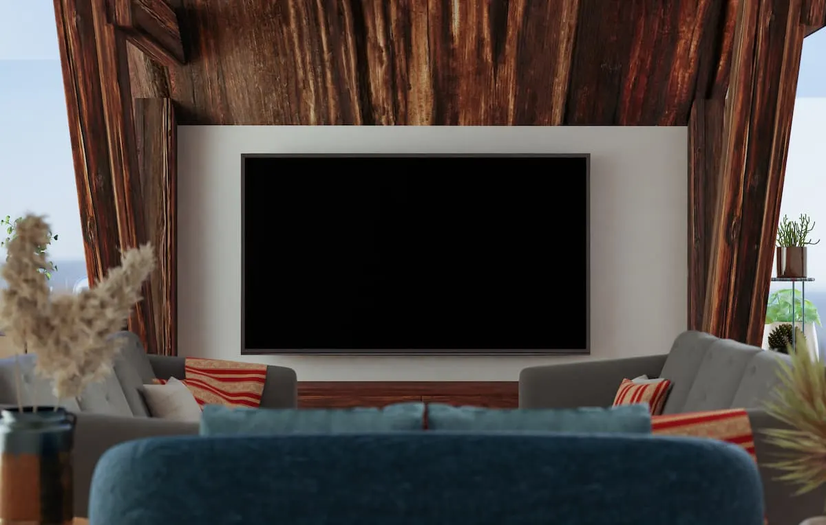 Televisor grande montado en la pared de un salón moderno con sofás y decoración de madera.