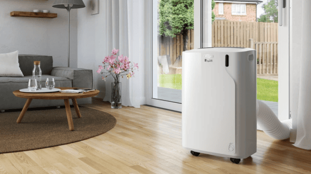 Aire acondicionado portátil De'Longhi instalado junto a una puerta de terraza en un salón luminoso