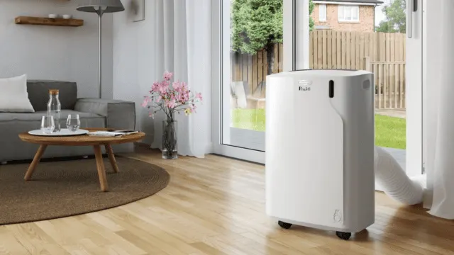 Aire acondicionado portátil De'Longhi instalado junto a una puerta de terraza en un salón luminoso