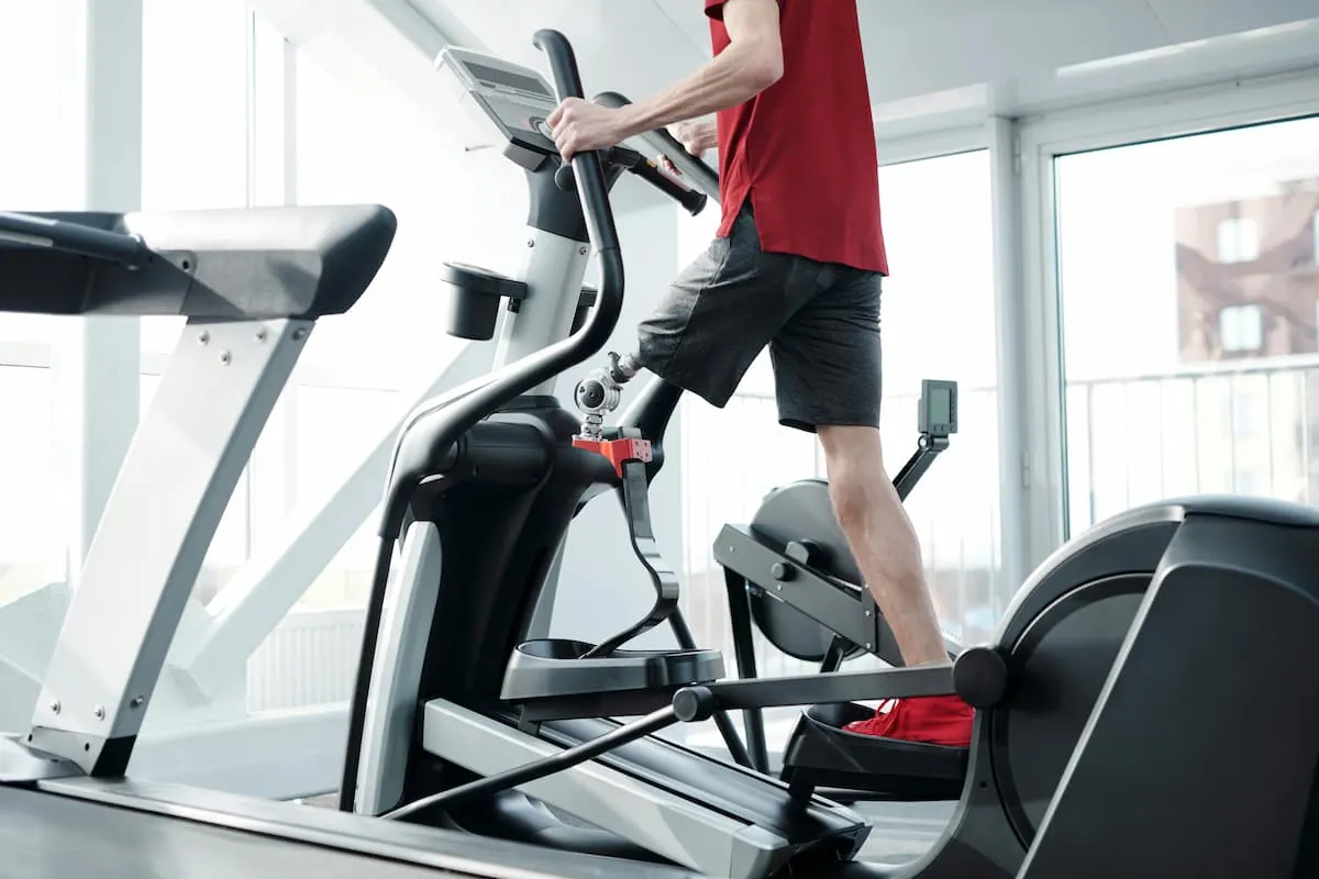 Hombre haciendo ejercicio en una máquina elíptica en el gimnasio.