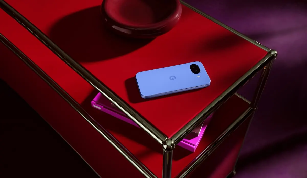 Google Pixel 10a color lavanda en mesa roja y estantería metálica