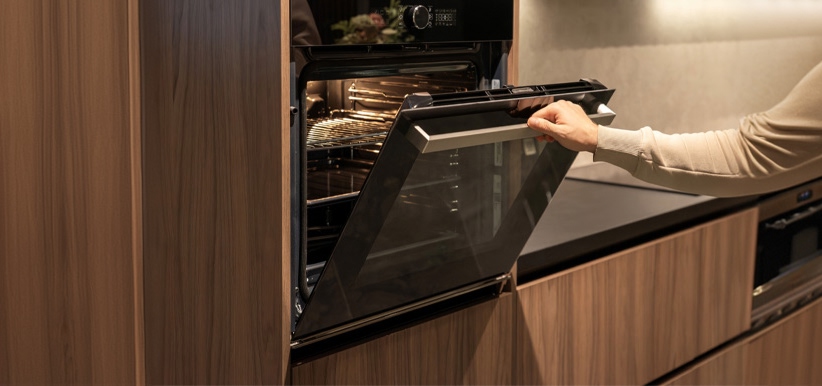 Hombre observando la cocción de galletas en un horno eléctrico empotrado.