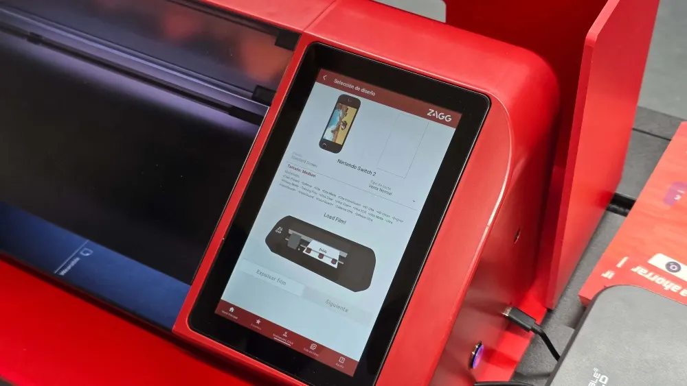 Primer plano de la máquina ZAGG roja en el Service Point de MediaMarkt, con una pantalla táctil mostrando la interfaz para seleccionar y cortar protectores de pantalla a medida.