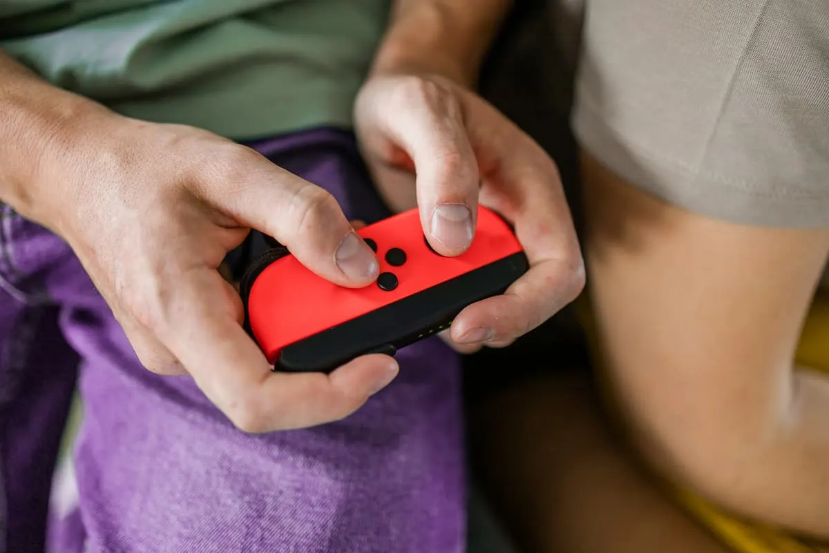 Persona sujetando un mando Joy-Con rojo de Nintendo Switch con ambas manos.