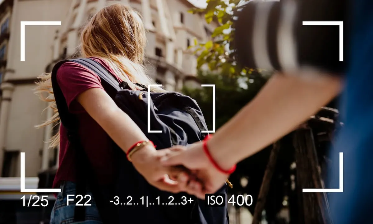 Vista de cámara de una persona con mochila caminando por la ciudad mientras toma de la mano a otra.