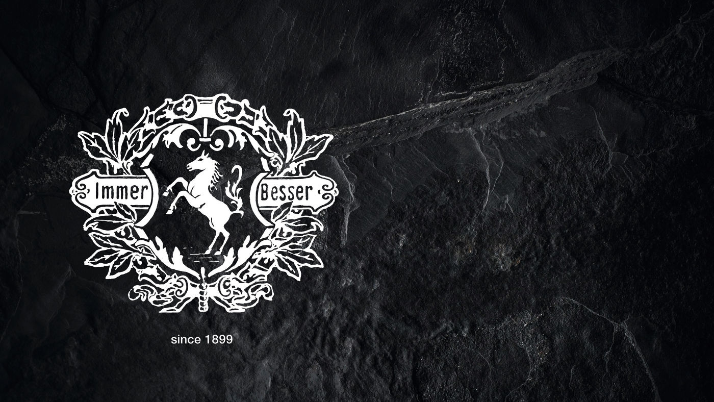 Emblema clásico de Miele con un caballo rampante y el lema "Immer Besser", sobre fondo oscuro.
