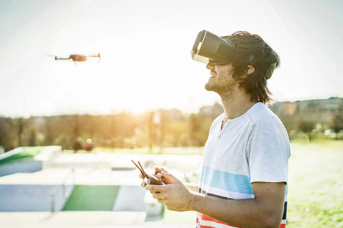 Hombre con gafas de realidad virtual controlando un dron al aire libre.