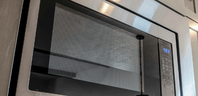 Microondas plateado empotrado con panel de control digital a la derecha, mostrando "4:08". La puerta es de cristal con rejilla.