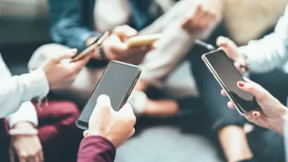 Un grupo de personas está usando teléfonos móviles. Las personas visten camisas blancas, azules y burdeos. Los teléfonos son negros.