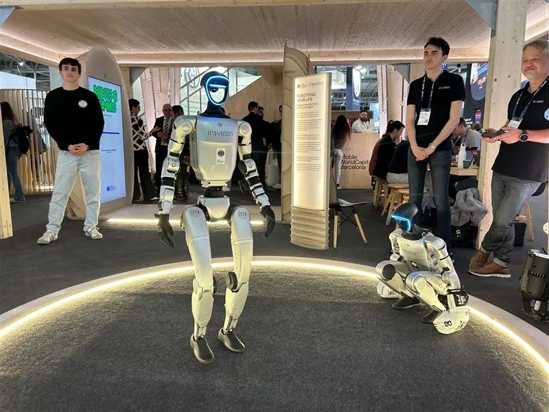 Robots humanoides exhibidos en el Mobile World Congress 2025, rodeados de asistentes en un stand de innovación tecnológica.