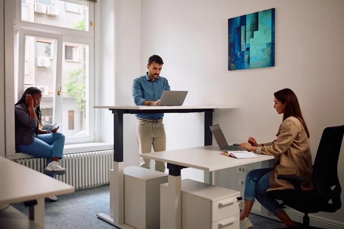 Personas trabajando en oficina con mesas elevables.
