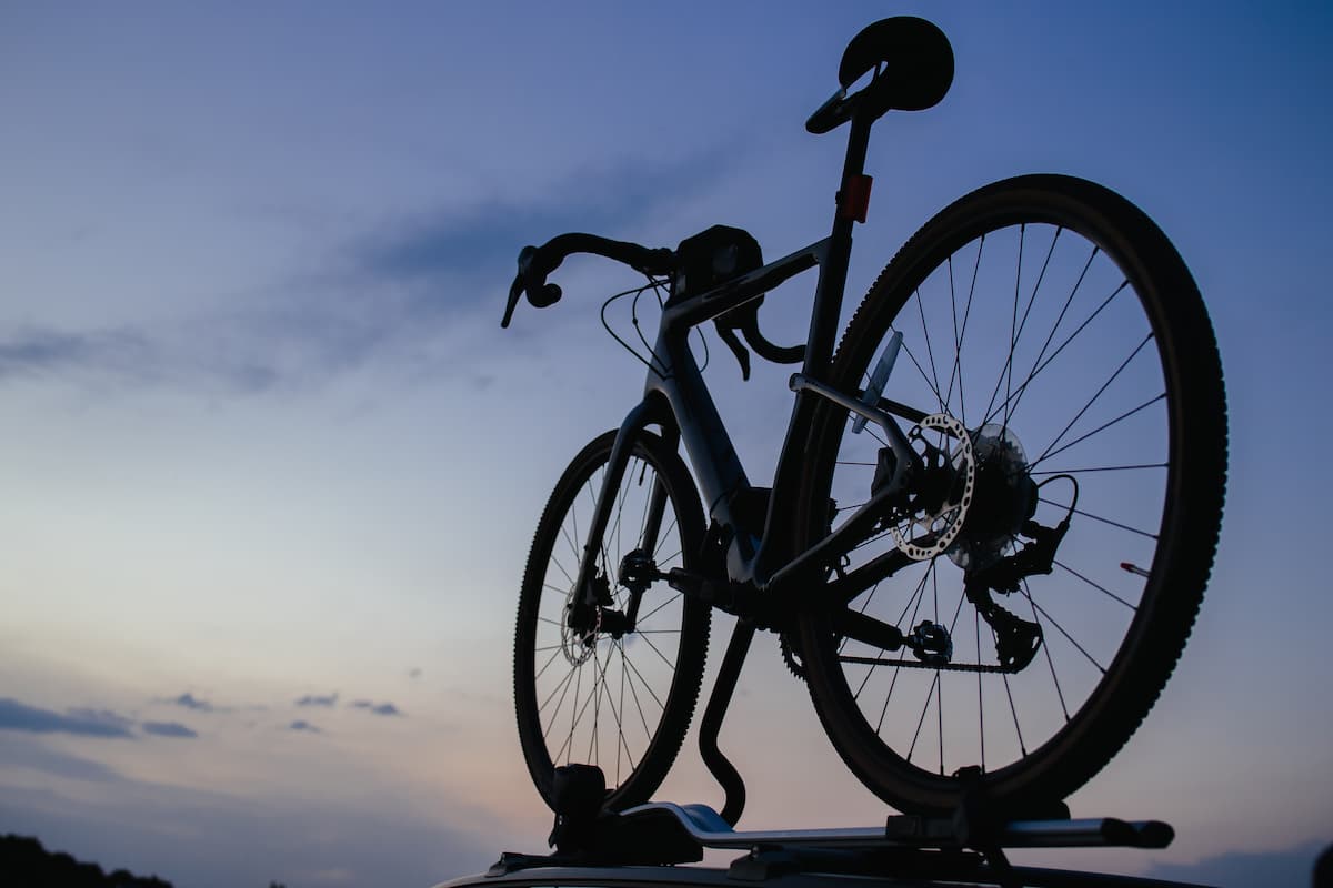 Silueta de una bicicleta montada en el techo de un auto al atardecer