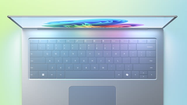 Vista superior de un portátil abierto parcialmente, con teclado iluminado y pantalla mostrando un remolino de colores sobre fondo degradado.