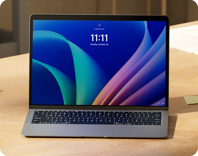 Laptop sobre un escritorio, mostrando la pantalla de inicio con un fondo azul y verde y la hora 11:11.