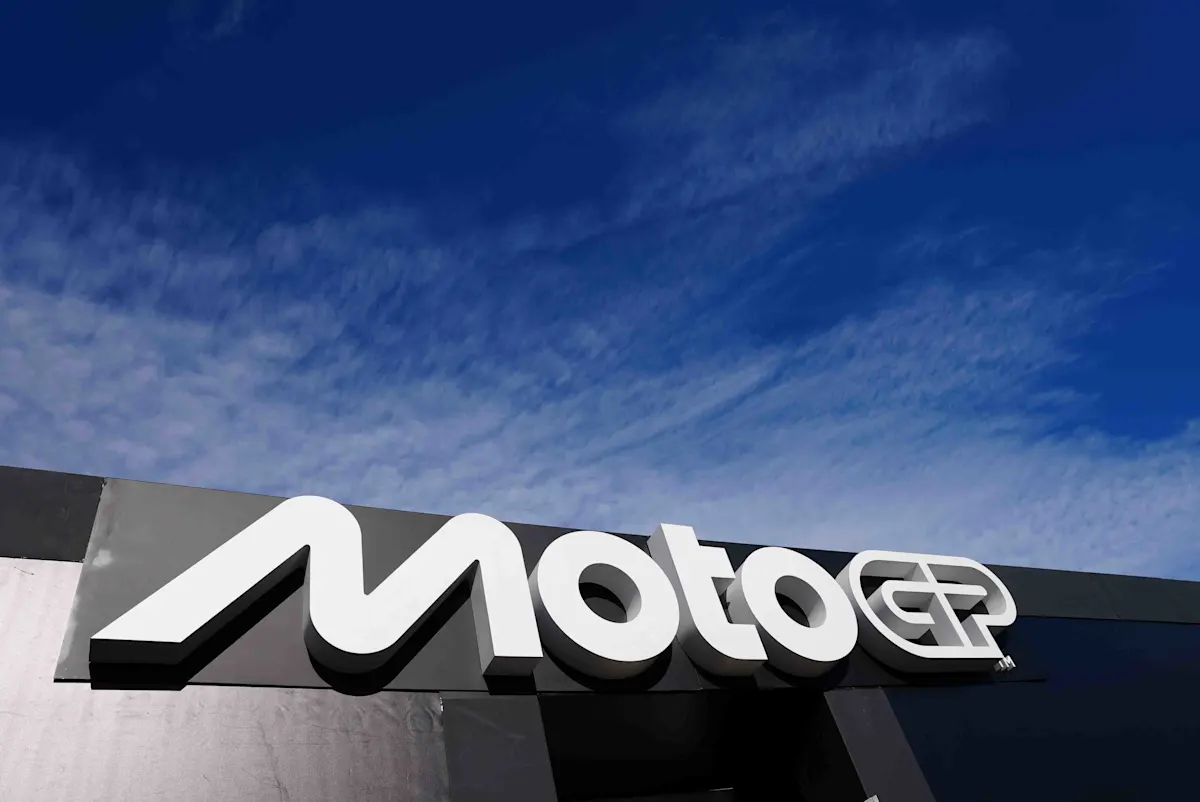 Logotipo de MotoGP en gran cartel blanco sobre cielo azul.