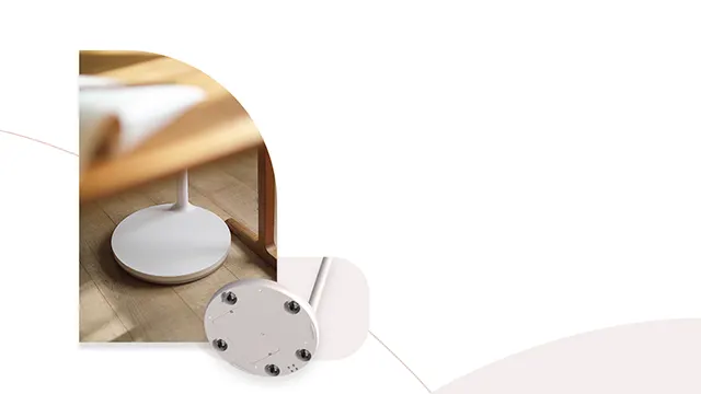 Base redonda blanca de lámpara bajo mueble de madera. Otra base blanca con tornillos visibles está en el suelo.