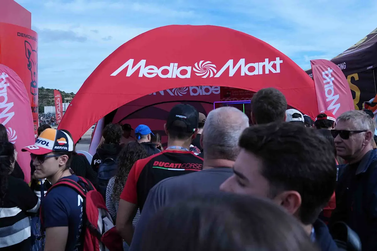 Público haciendo cola frente a la carpa roja de MediaMarkt en la Fan Zone del MotoGP de Valencia.