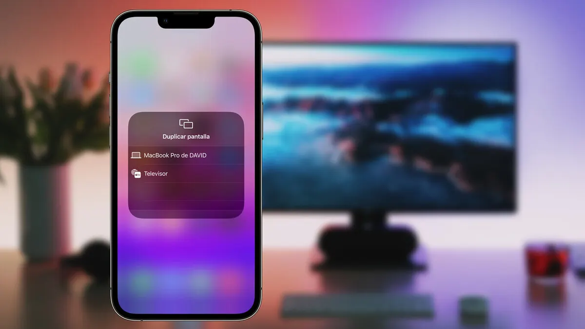 Un teléfono muestra un menú para duplicar pantalla con opciones para "MacBook Pro de DAVID" y "Televisor". Al fondo, un monitor.
