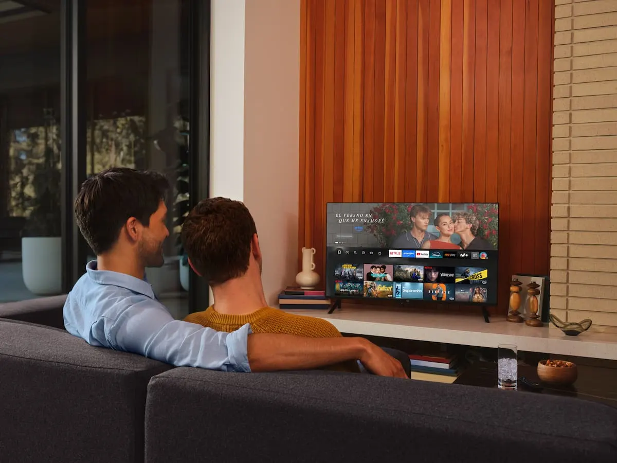 Dos personas viendo contenido en streaming en un televisor con Fire TV desde el sofá del salón